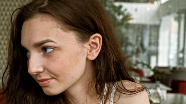 Lächelnde-russische-Frau-mit-Blick-auf,-während-sie-in-einem-ruhigen-Großstadtcafé-mit-sanfter-natürlicher-Beleuchtung-sitzt.-Mittlere-Nahaufnahme-schuss-auf-4k-Handheld