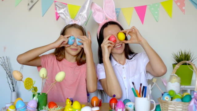 Mother-and-her-little-daughter-painting-eggs.-Happy-family-preparing-for-Easter.