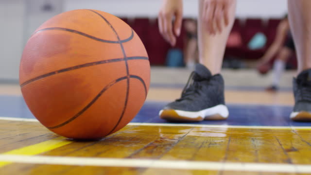 Low-Section-of-Female-Basketball-Spieler-binden-Shoelace-und-Taking-Ball