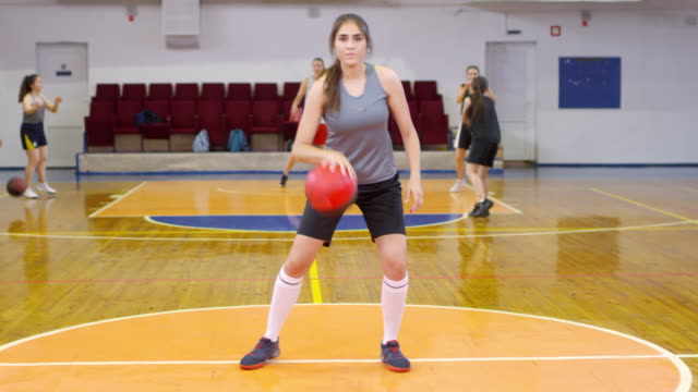Junge-Sportlerin-dribbelt-einen-Basketball-und-posiert-für-Kamera