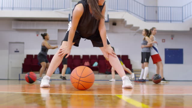 Junge-Basketballspielerin-dehnt-Beine-auf-dem-Platz