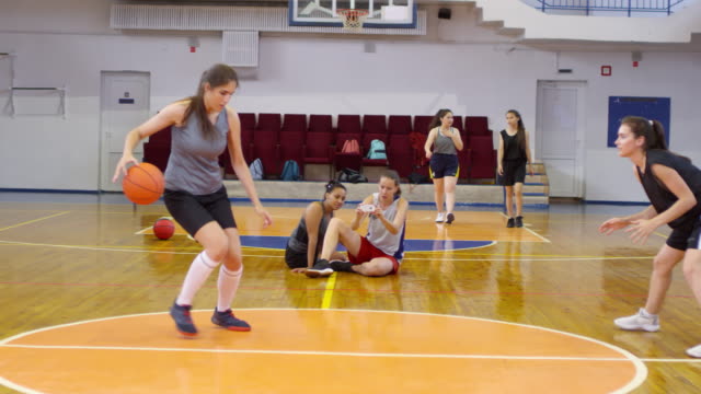 Young-Female-Athletes-Having-Partner-Workout-with-Basketball-on-Court
