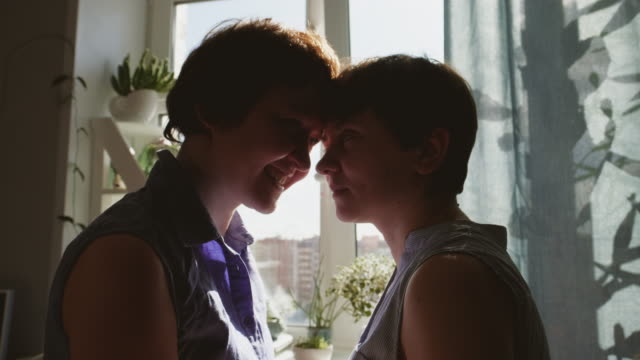 Dos-mujeres-jóvenes-se-abrazan-y-se-besan-en-casa.-Ropa-casual.-Pareja-lesbiana,-relaciones-homosexuales,-amor-entre-personas-del-mismo-sexo.