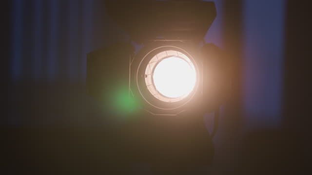 Spotlight-with-Fresnel-lens-slowly-turn-turns-on-and-off-in-front-of-black-background
