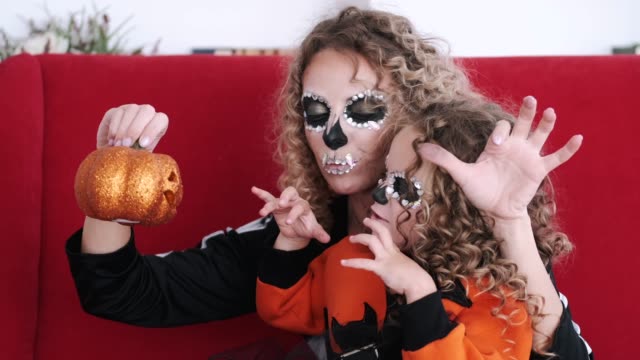 Daughter-and-mom-in-halloween-costumes-play-on-red-sofa