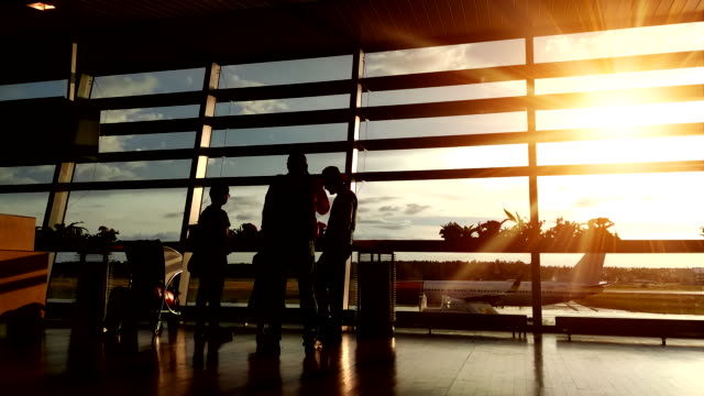 Silhouetten-von-Passagieren-in-der-Flughafenlounge-bei-Sonnenuntergang