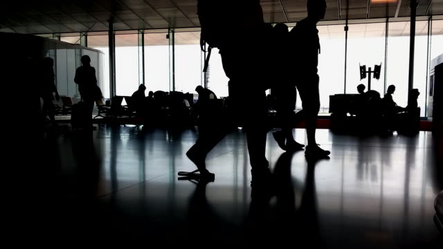 Silhouettes-of-passengers-in-the-airport-lounge-during-sunset