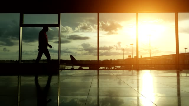 Silhouetten-der-Passagiere-am-Flughafen-bei-Sonnenuntergang