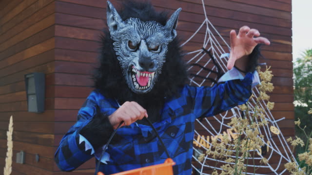 Portrait-Of-Boy-Wearing-Fancy-Dress-Werewolf-Mask-Outside-House-Collecting-Candy-For-Trick-Or-Treat