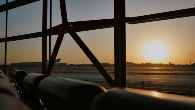 Silhouette-eines-Flugzeugs,-das-bei-Sonnenuntergang-am-Flughafen-Peking-im-Hintergrund-eines-Fensters-abstartet
