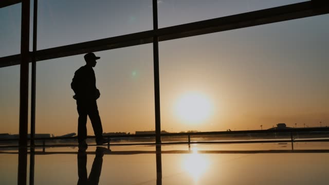 Silhouette-eines-Touristen-Kerl-der-Take-off-stehenden-Flugzeug-am-Flughafen-Fenster-bei-Sonnenuntergang-am-Abend-beobachten.-Reisekonzept,-Menschen-am-Flughafen