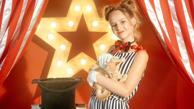 Cheerful-young-girl-magician-is-holding-kitten-in-hands