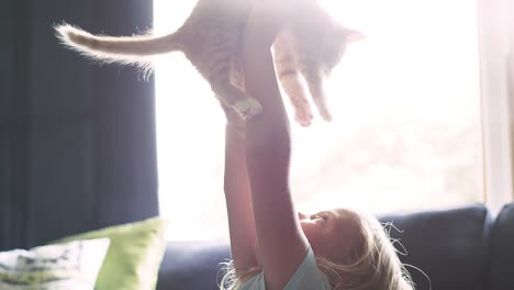 A-little-girl-holding-a-cat-up-above-her-head-and-then-giving-it-a-hug