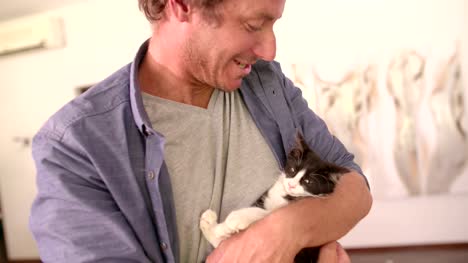 Moderne-Vater-Halten-Katze-auf-seinen-Armen-und-Lächeln