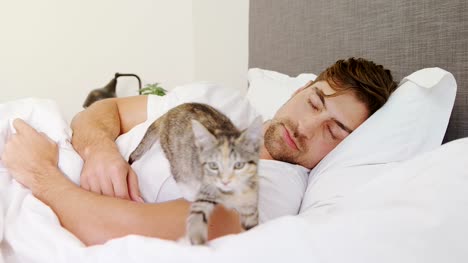 Junger-Mann-schlafen-im-Bett-halten-Katze-in-seine-Arme-4K-4k