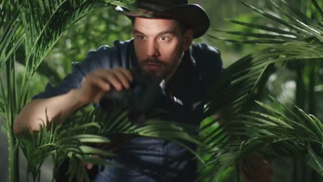 Aventurero-con-sombrero-caminando-por-la-selva-bosque-y-mirando-a-través-de-binoculares