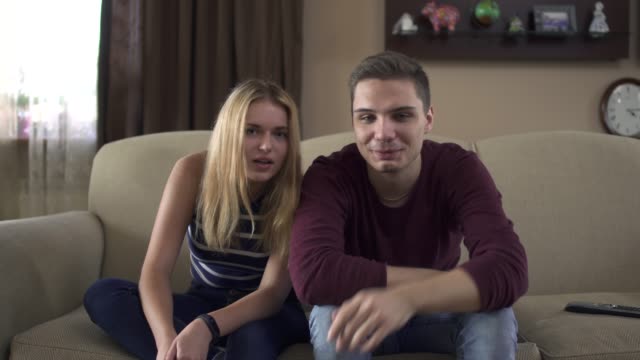 Young-couple-of-teenagers-watching-tv-at-home
