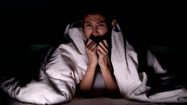 Frau-Horror-Film-allein-im-Bett.-Asiatische-Frau-liegend-im-Bett-allein,-Überraschung-und-Schock-von-scary-Movie.-Halloween-allein-Wohnkonzept.