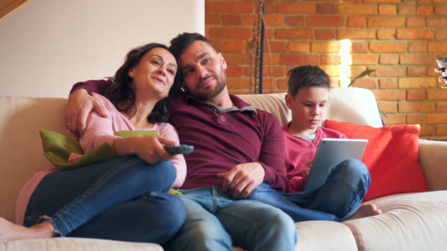 Eltern,-die-vor-dem-Fernseher-während-Sohn-mit-digital-Tablette-zu-Hause