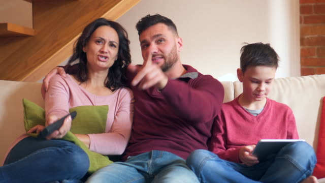 Junge-mit-digital-Tablette-während-seiner-Eltern-vor-dem-Fernseher