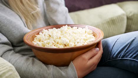 Frau-essen-Popcorn-sitzt-auf-dem-Sofa-im-Wohnzimmer
