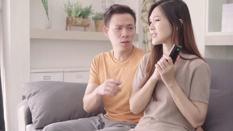 Asian-couple-argue-while-watching-TV-in-living-room-at-home,-sweet-couple-have-angry-moment-while-lying-on-the-sofa-when-relax-at-home.-Lifestyle-couple-relax-at-home-concept.