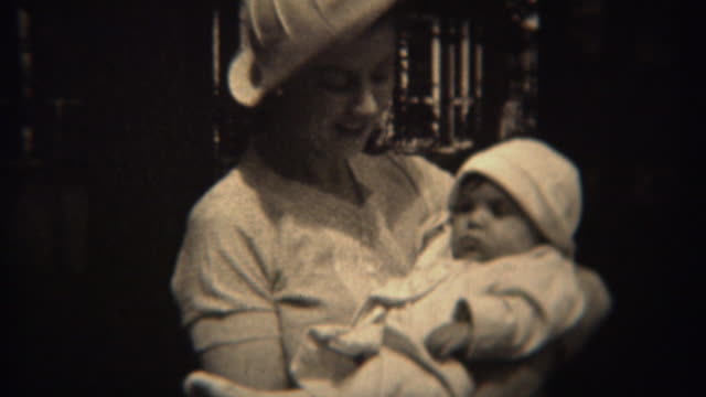 1937:-Mother-in-white-fashion-hat-holding-baby-daughter-in-matching-outfit.