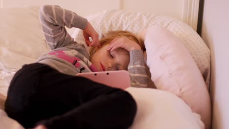 Una-niña-pequeña-que-descansan-en-su-dormitorio-piso-mientras-disfruta-de-un-programa-en-su-portátil-con-sistema-de-juegos