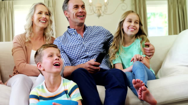 Glückliche-Familie-vor-dem-Fernseher-im-Wohnzimmer