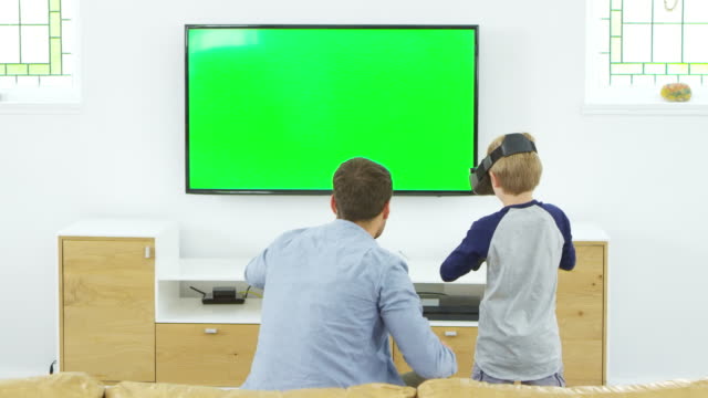 Vater-und-Sohn-spielen-Computerspiel-mit-Virtual-Reality-Kopfhörer