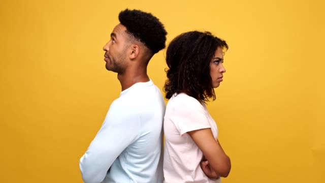 Afro-americano-pareja-permanente-hacia-atrás-molesto-y-decepcionado-aislaron-sobre-fondo-amarillo