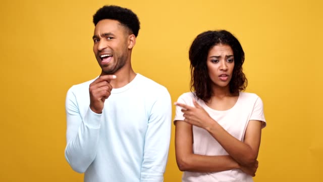Junge-Afro-amerikanische-Ehepaar-gegenseitig-die-Schuld-und-Schuldzuweisungen-stehen-auf-gelbem-Hintergrund-isoliert