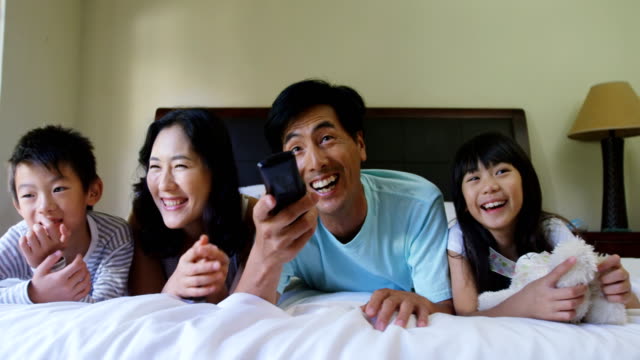 Glückliche-Familie-vor-dem-Fernseher-im-Schlafzimmer-4k