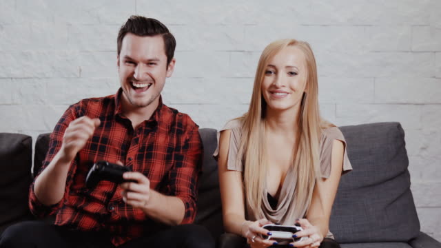 young-man-and-woman-are-sitting-on-the-couch-and-are-playing-a-game