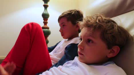 Die-jungen-sitzen-auf-dem-Sofa-vor-dem-Fernseher-hinter-der-Kamera.-4K-candid-Clip-von-Kindern,-die-auf-Bildschirm-zu-Hause
