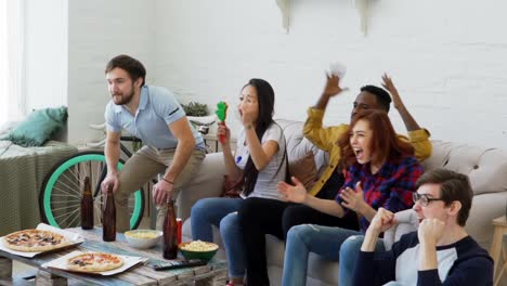 Slow-motion-of-group-of-happy-friends-watching-sports-game-on-TV-at-home.-They-are-yelling-while-their-favorite-team-win-competition