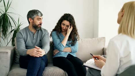Angry-man-arguing-and-talking-about-his-wife-to-marriage-counselor.-Young-couple-visiting-professional-psychologist-office