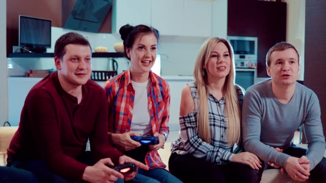 Happy-couples-in-love-people-enjoy-relaxing-by-playing-videogames-with-wireless-controllers-and-having-fun-indoor-in-modern-flat