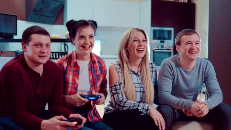 Feliz-grupo-de-amigos-masculinos-y-femeninos-jugando-videojuegos-con-controladores-inalámbricos-de-risa