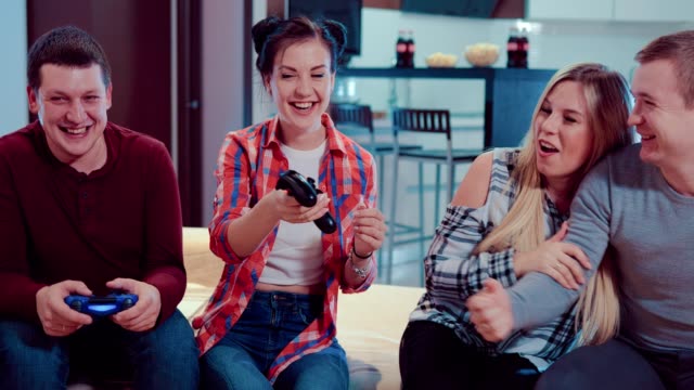 Glückliche-Gesellschaft-der-Freunde-entspannen-durch-Videospiele-spielen-und-Spaß-haben-in-modernen-Wohnung-innen
