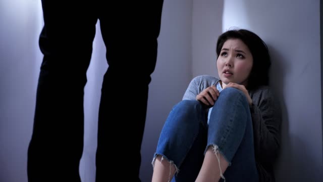 Triste-mujer-asiática-sienta-en-el-piso,-enojado-marido-amenaza,-conflicto-en-la-familia,-violencia-50-fps