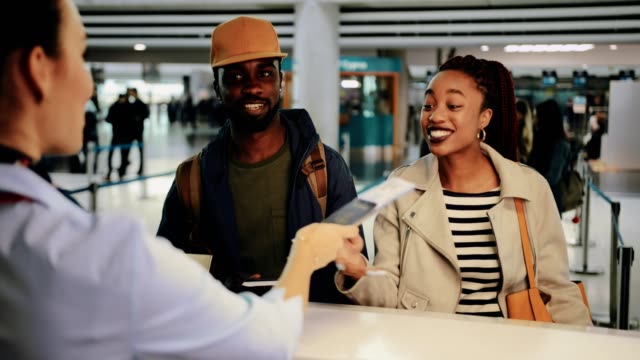 Young-couple-taking-boarding-passes-at-airport-check-in-desk