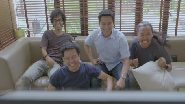 Grupo-de-asiático-plana-compañeros-ver-competición-de-los-deportes-en-la-TV-en-casa