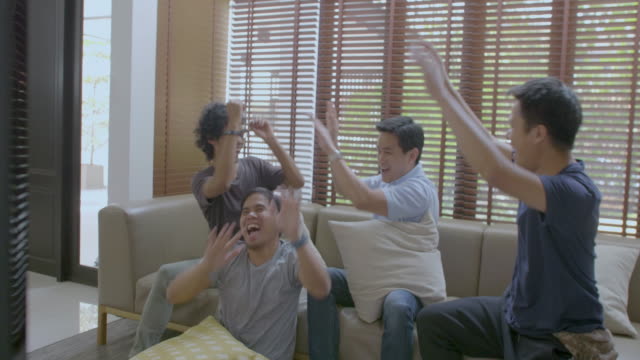 Group-of-asian-flat-mates-watching-sports-competition-on-TV-at-home