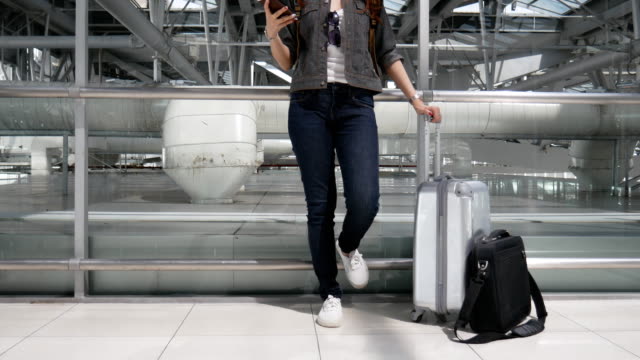 Frau-mit-Smartphone-und-Take-Off-Flug-mit-Gepäck-und-Gepäck-am-Flughafen-warten-hautnah.-Menschen-und-Lebensweisen-Konzept.-Technologie-und-Trravel-Thema.
