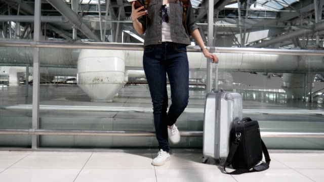 Cerca-mujer-usando-teléfonos-inteligentes-y-esperando-para-despegar-vuelo-con-maletas-y-equipaje-en-el-aeropuerto.-Concepto-de-personas-y-estilos-de-vida.-Tema-tecnología-y-trravel.