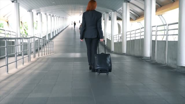 Tiro-de-cámara-lenta-de-joven-mujer-de-negocios-asiáticos-atractivos-arrastrando-una-maleta-con-ruedas-en-el-aeropuerto-para-viaje-de-negocios