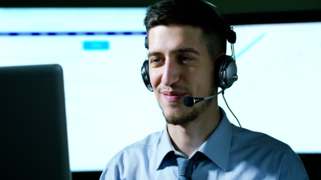 A-young-man,who-work-in-customer-service-or-in-some-airport-control-tower-station,-answers-calls-to-phone-customers-with-a-smile-day-and-night.