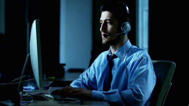 Ein-junger-Mann,-der-im-Kundenservice-oder-in-einigen-Flughafenbahnhof-Kontrollturm-arbeiten,-beantwortet-Anrufe-auf-Handy-Kunden-mit-einem-Lächeln-Tag-und-Nacht.