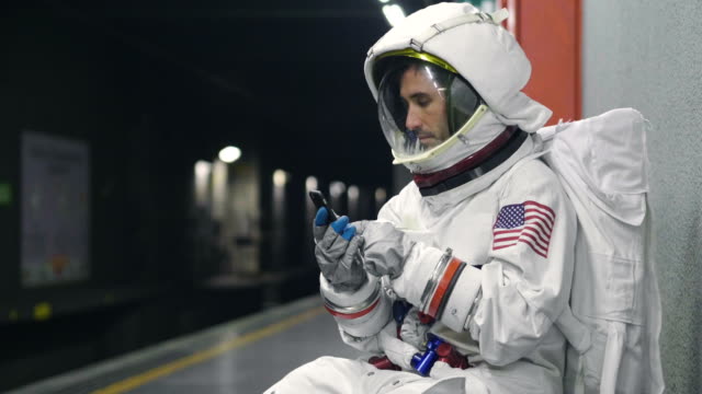 Ein-Astronaut-gekleidet-Mann-nutzt-das-Smartphone-anrufen-und-Nachrichten-senden.-Der-Astronaut-lächelt-beim-Betrachten-des-Telefons-in-der-Hand.